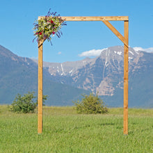 Load image into Gallery viewer, Wedding arch for rent at the Rugged Horizon wedding venue in St. Ignatius, MT. This piece measures 6 feet wide by 8 feet tall. It is constructed of solid wood with a dark stain. There are cross-members on the sides that work well for hanging a large bouquet of flowers or draping fabric. We have tulle available for rent, or you may bring your own sheers.
